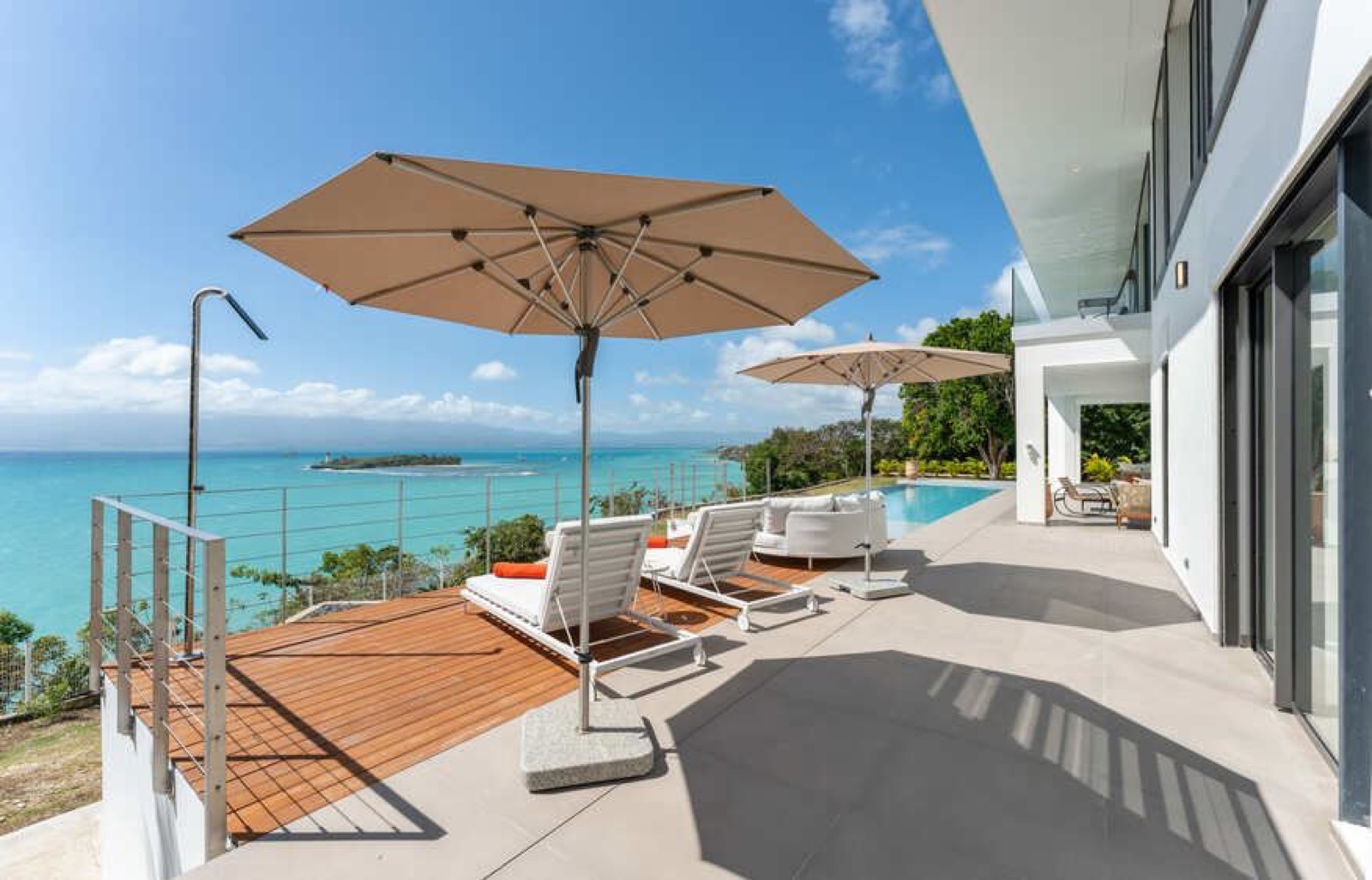 Villa Guacania — terrasse avec parasols et piscine surplombant la mer et l'îlet au Gosier